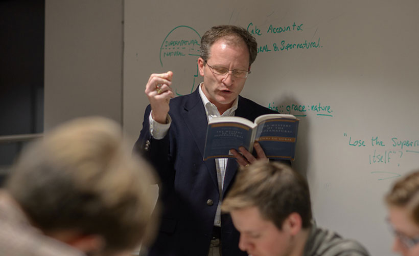 Professor reading book in front of class