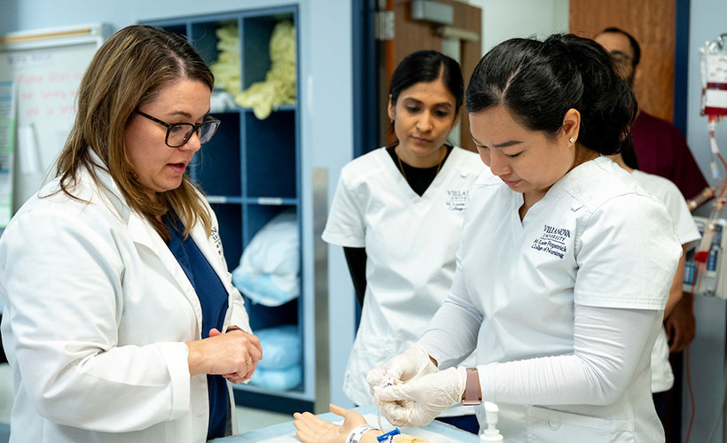 Nursing professor and students working with patient simulation mannequin