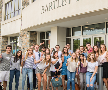 students smiling in front of business school