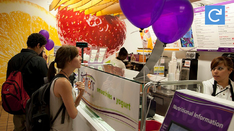 Several students are ordering food in front of the store counter.