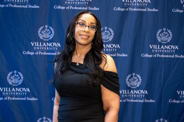 Tracey Barnes in front of a Villanova University College of Professional Studies banner