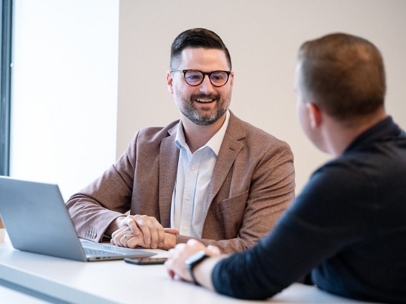 two colleagues conversing in front of a laptop