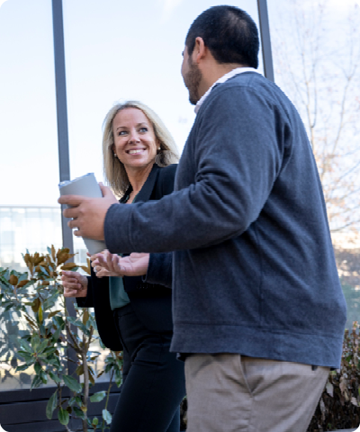 woman in a blazer smiling and walking with a colleague