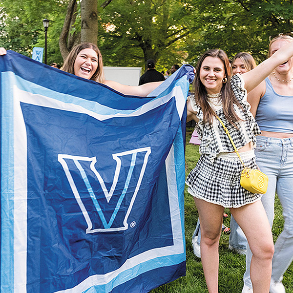  female students hold up a giant blue Villanova flag