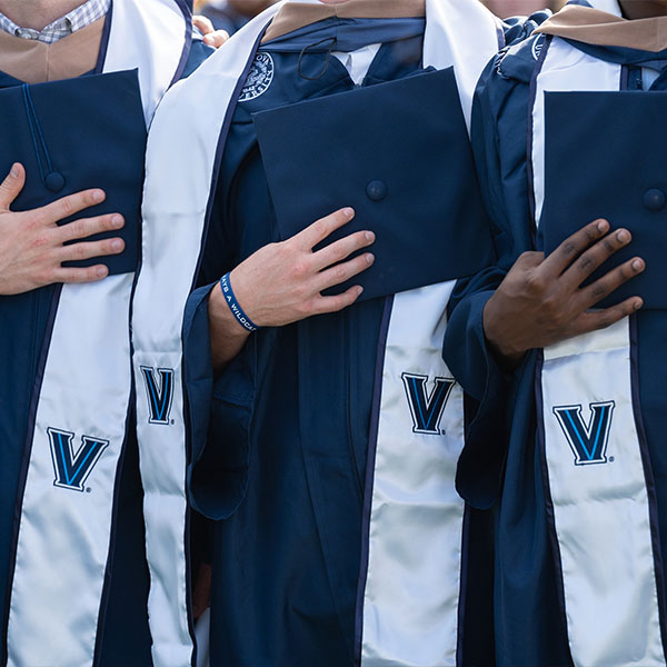 three hands on their hearts during the Pledge of Allegiance at Commencement