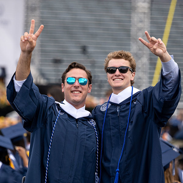 two male Villanova graduates wearing sunglasses and standing side-by-side give Vs up