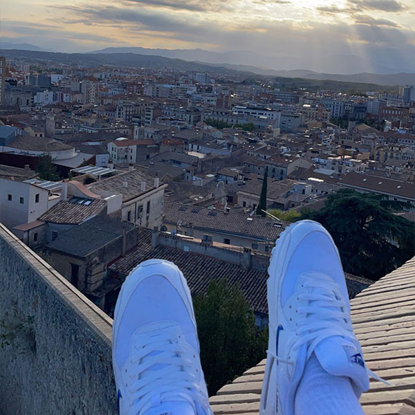 rooftop view of a person wearing a pair of white sneakers 