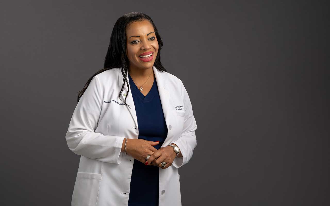 Lt. Cmdr. Akeeka Davis standing in her white Villanova lab coat and blue nursing scrubs