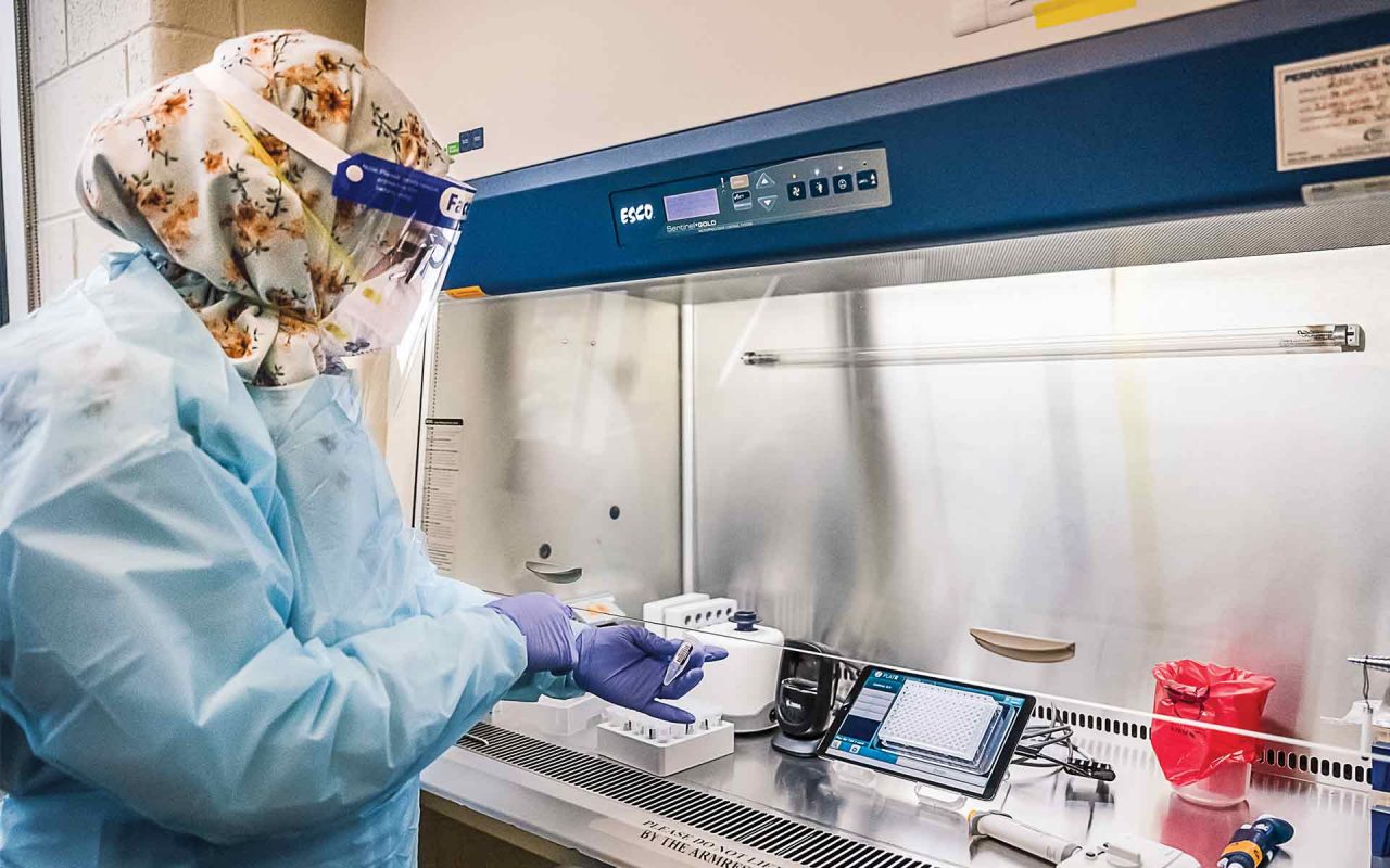 a woman in full PPE working in the PCR testing lab