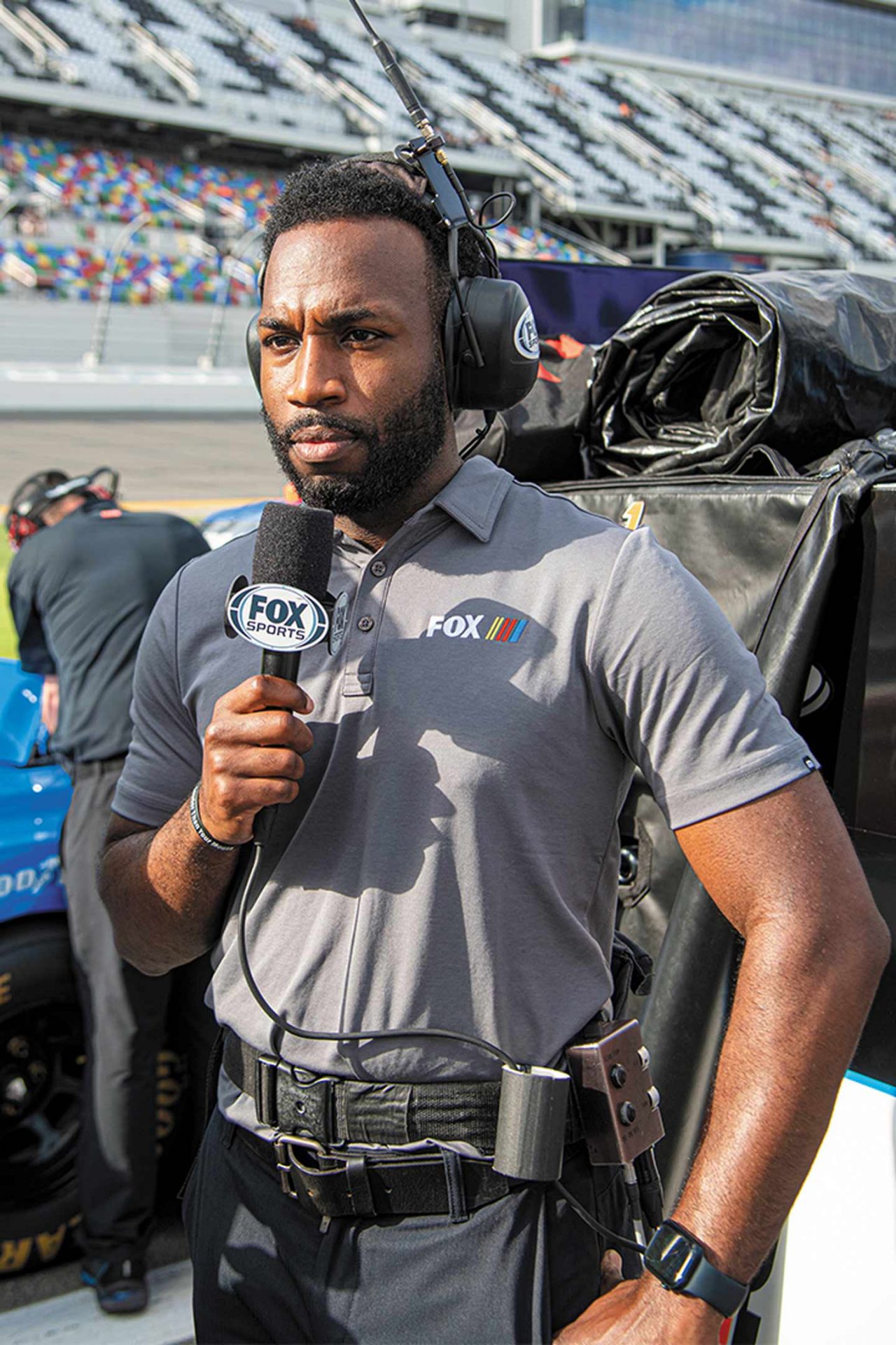 NASCAR reporter Josh Sims holding a FOX Sports microphone on the sidelines of a race track