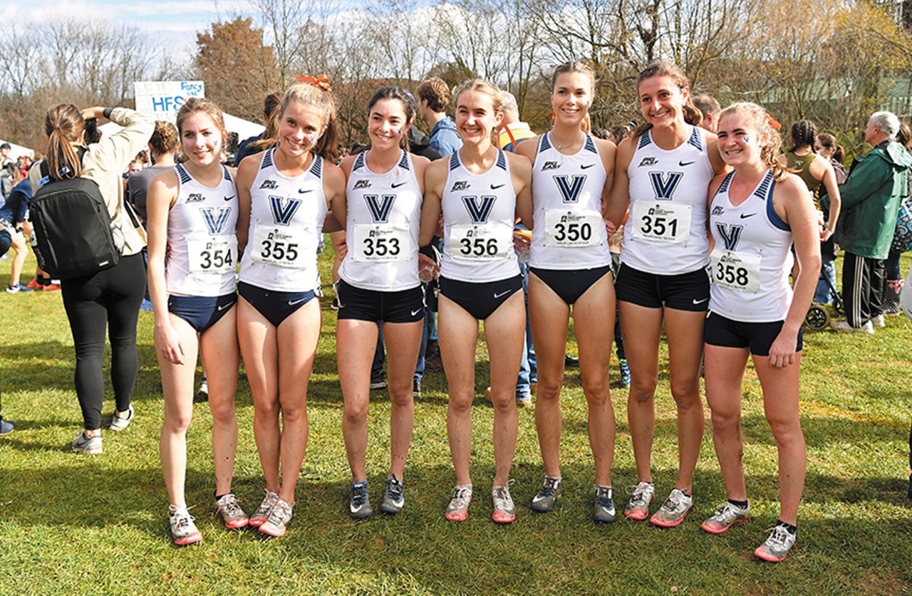 Villanova's Women's Cross Country team standing arm to arm in their uniforms at an outdoors running event
