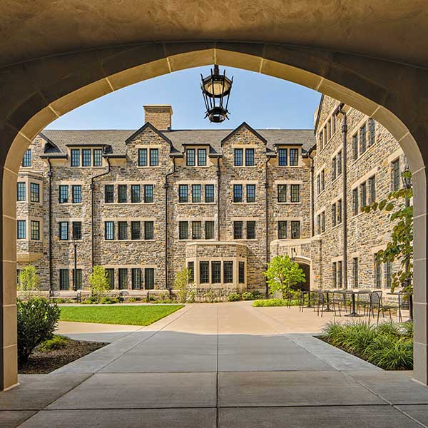 a stone arch frames an outside view of the Commons residence hall 