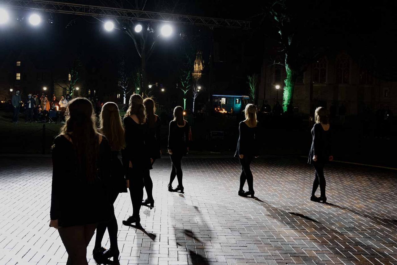 the Villanova Irish Dance Team photographed from behind as they perform outside at night
