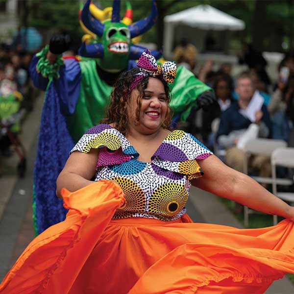 Woman in a bright orange skirt during a costumed ceremony.