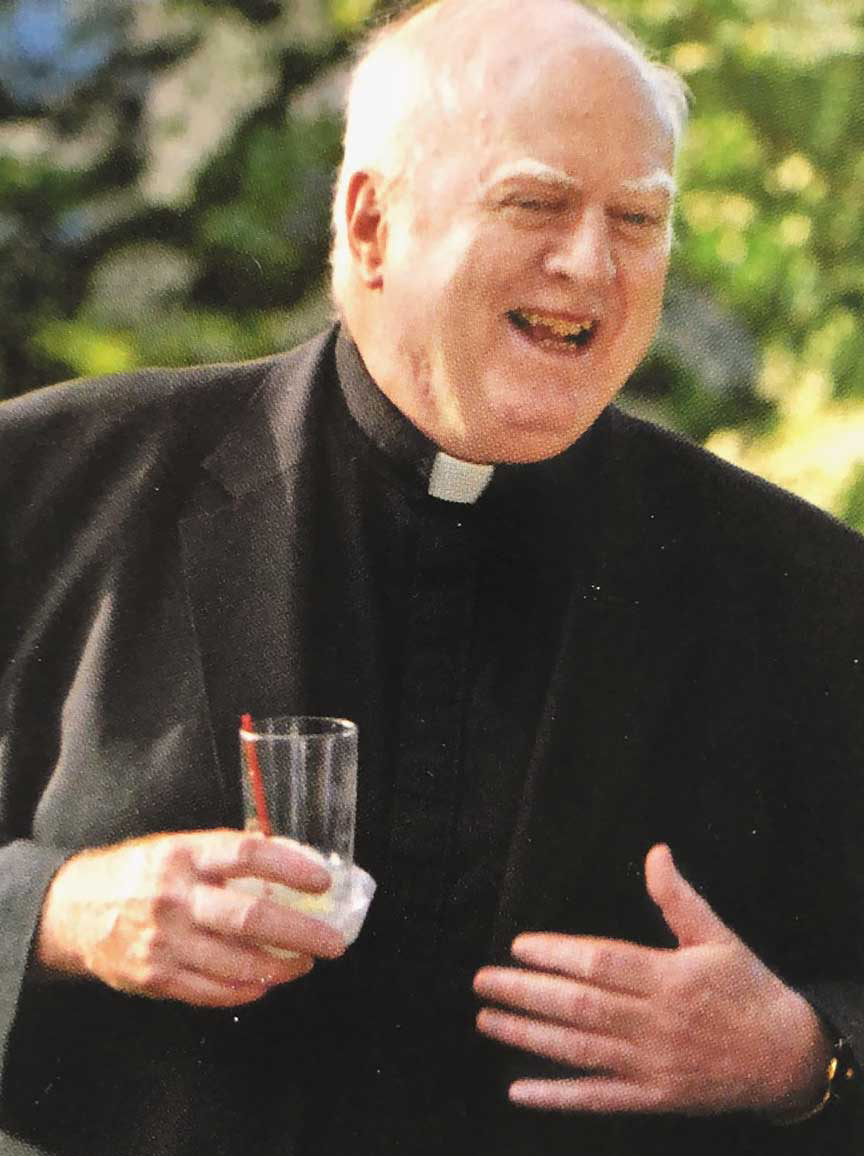 the Rev. John P. Stack laughing and holding drink in hand