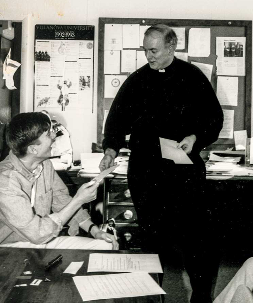 black-and-white photo of the Rev. John P. Stack in his office with a student