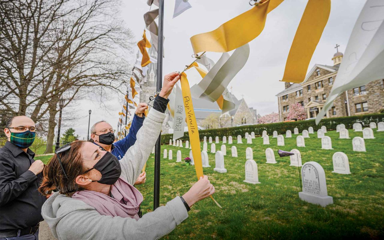 three members of the Villanova community look at ribbons hung as part of a COVID-19 memorial