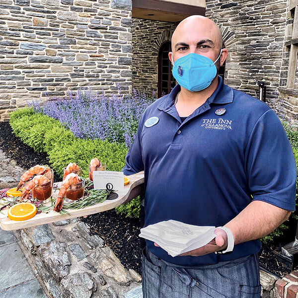 male staff member of The Inn at Villanova holding napkins and a tray of food