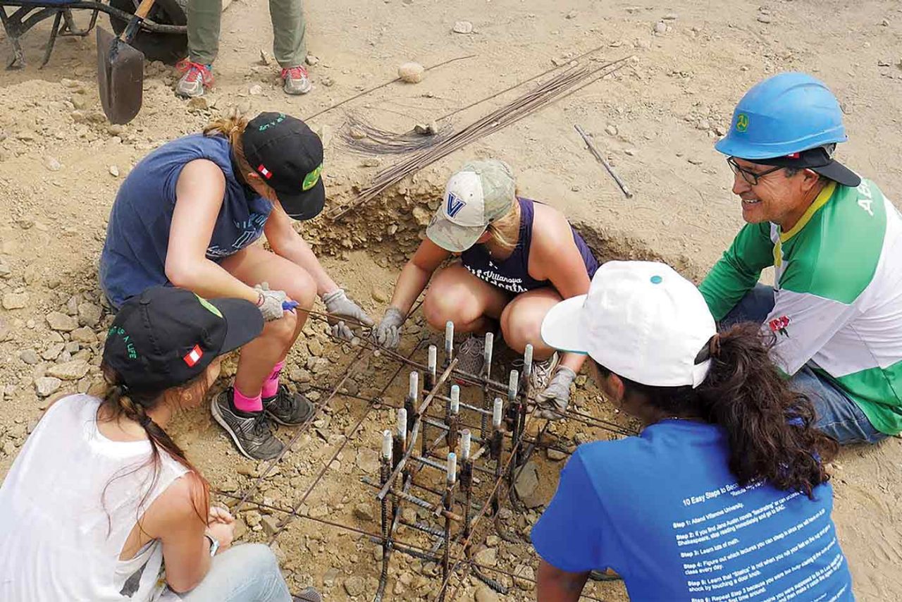 Five engineers sitting outside in dirt installing the foundation for a wind turbine in Peru