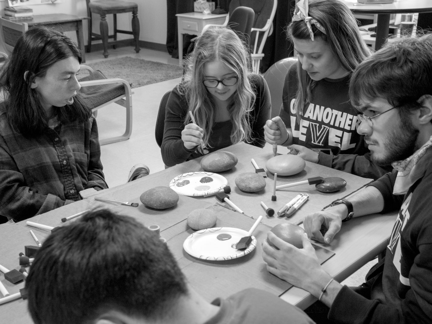 Black-and-white photo of Villanova’s LEVEL students painting rocks with students from the Community School of Davidson.