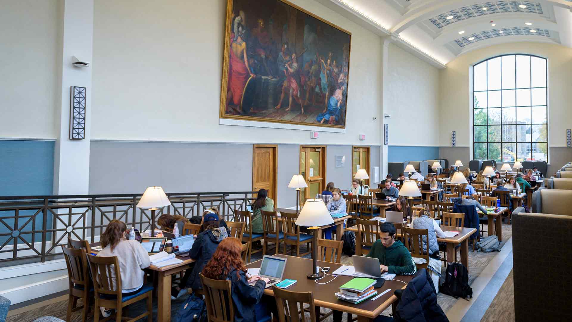 Students in the Falvey Library's Dugan Polk Family Reading Room sit at tables studying.