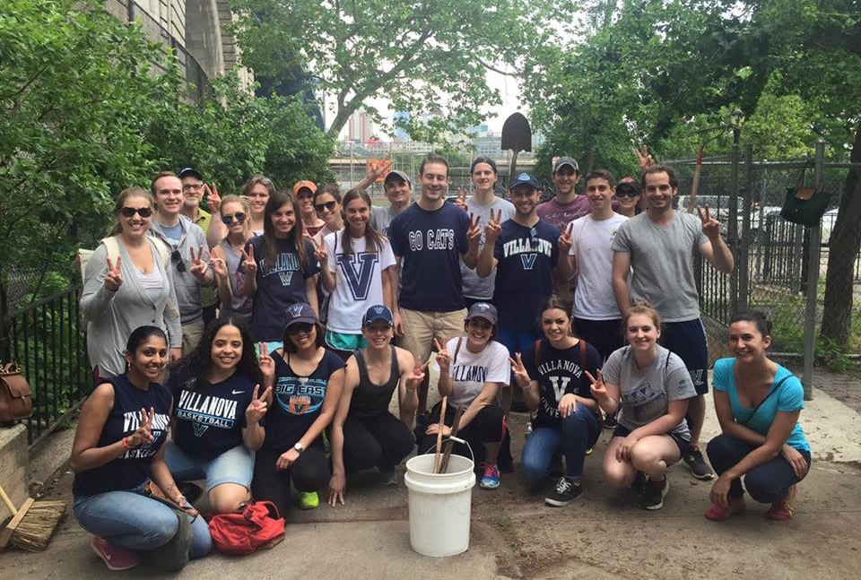 Group of Villanova alumni with their "V"s up, posing with shovels, buckets and other gardening items