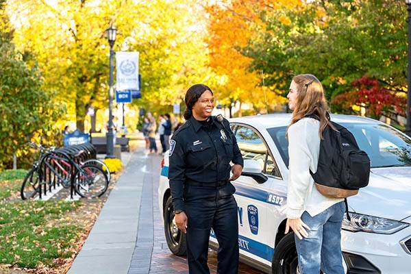 A public safety officers speaks outside with a student. 
