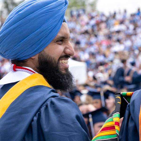 a bearded male Villanova graduate smiles amidst the crowd at Commencement
