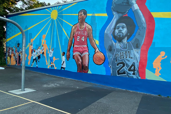 a colorful playground mural depicts Walter Jones playing basketball for the Philadelphia 76ers